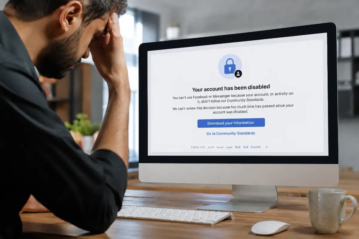 An image showing a man sitting in front of a computer screen showing a Facebook account has been disabled message.